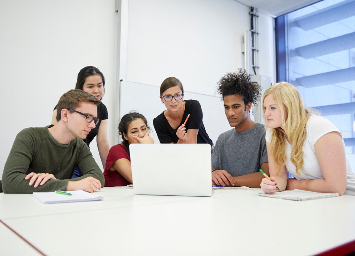 Studierende mit Dozentin am Schreibtisch